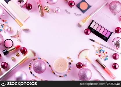 Festive make up products on pink background, flat lay frame with copy space. Festive make up
