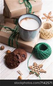 festive mood. Gifts, cup cappuccino and Christmas decor on the wooden background.
