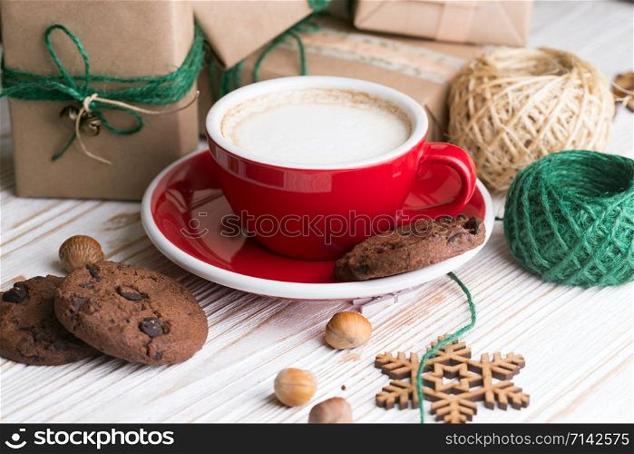 festive mood. Gifts, cup cappuccino and Christmas decor on the wooden background.