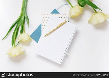 Festive spring composition: yellow tulips, a notebook with a pen, on a white background. the concept of spring holidays of a freelancer or blogger