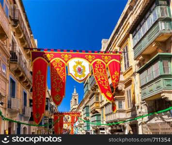Festive standards and flags in the medieval narrow streets of Valletta on a sunny morning. Malta.. Malta. Holiday standards and flags in the old narrow streets of Valletta.