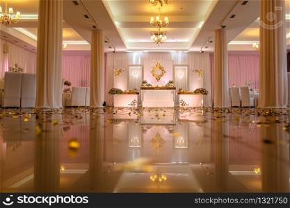 Festive table decorated with composition of white, red and pink flowers and greenery in the banquet hall. Table newlyweds in the banquet area on wedding party.. Festive table decorated with composition of white, red and pink flowers and greenery in the banquet hall.
