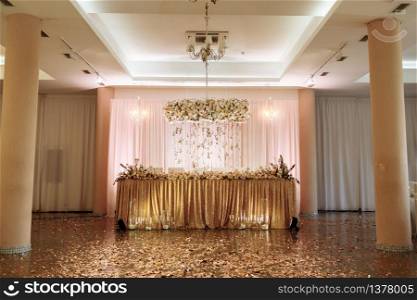 festive table for the bride and groom decorated with gold cloth and white flowers. wedding luxury decoration in the restaurant. selective focus.. festive table for the bride and groom decorated with gold cloth and white flowers. wedding luxury decoration in the restaurant. selective focus