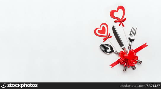 Festive table place setting with cutlery and red ribbon and hearts on white background, banner. Layout for Valentines day dinner invitation or anniversary, banquet, celebration, event