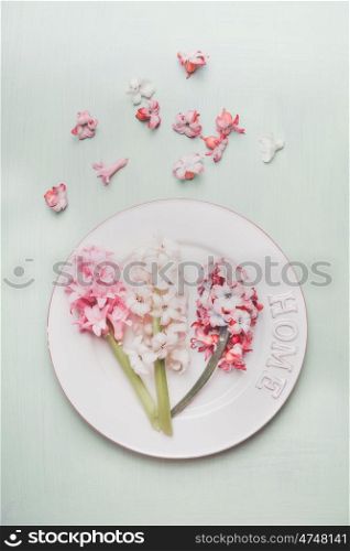 Festive table place setting with hyacinths and plate on light pastel wooden background, top view.