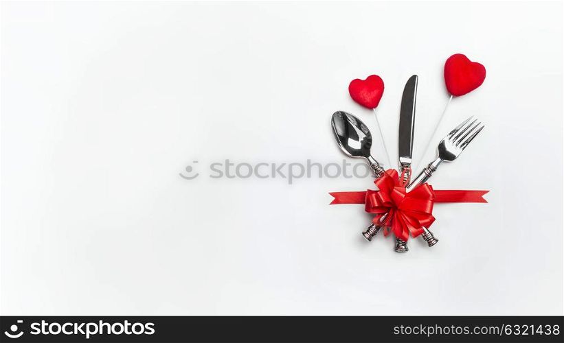 Festive table place setting with red bow , cutlery and two hearts on white background, banner. Layout for Valentines day dinner invitation or menu or anniversary, banquet, celebration, event