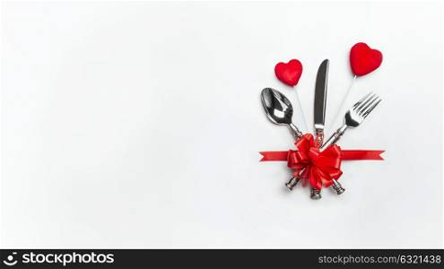 Festive table place setting with red bow , cutlery and two hearts on white background, banner. Layout for Valentines day dinner invitation or menu or anniversary, banquet, celebration, event