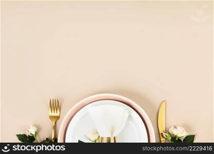 Festive table setting. Plates and cutlery with white linen napkin on beige background. Beautiful flat lay arrangement. Copy space