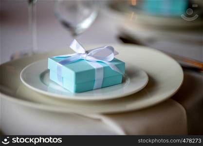 Festive table setting with handmade gift box on plate. Light blue handmade gift box in plate on wedding table.