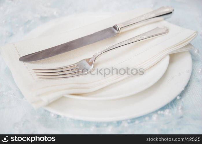 Festive table: silver knife and fork as well as a linen napkin are on the white porcelain plate