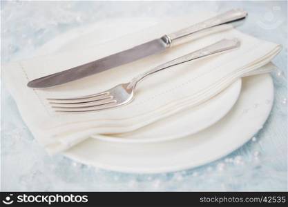 Festive table: silver knife and fork as well as a linen napkin are on the white porcelain plate