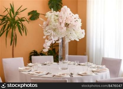 festive wedding decoration. Beautiful fresh white and pink flowers in glass vase on dining table on wedding day. High quality photo.. festive wedding decoration. Beautiful fresh white and pink flowers in glass vase on dining table on wedding day. High quality photo