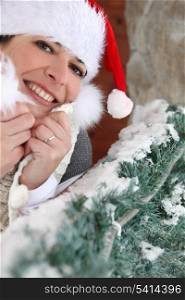 Festive woman stood in Santa hat by tree