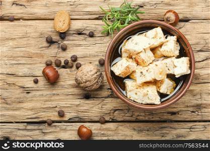 Feta cheese with herbs and garlic on old wooden background. Homemade feta cheese with herbs