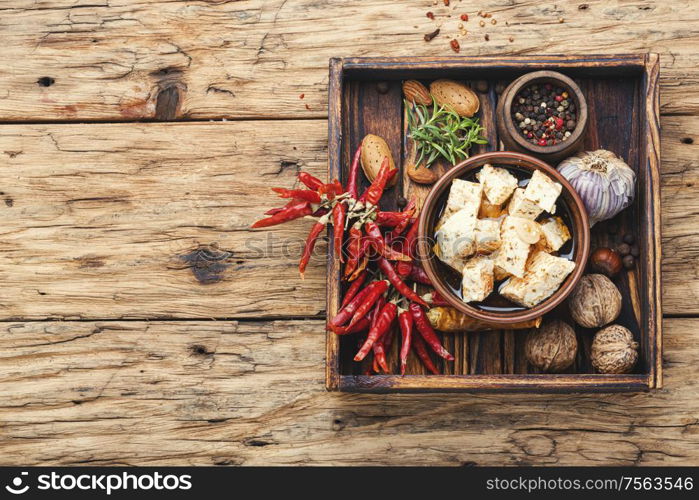 Feta cheese with herbs and garlic on old wooden background. Homemade feta cheese with herbs