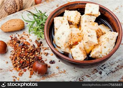 Feta cheese with herbs and garlic on old wooden background. Homemade feta cheese with herbs