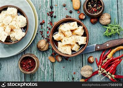 Feta cheese with spice and garlic on old wooden background. Feta cheese with herbs