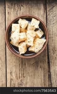 Feta cheese with spice and garlic on old wooden background. Homemade feta cheese with herbs