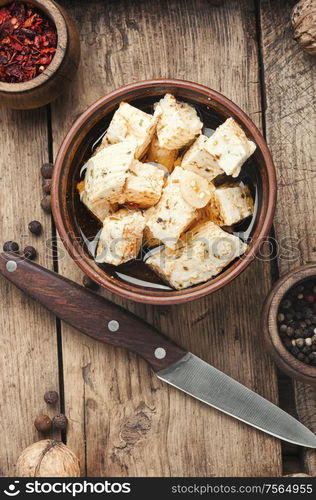 Feta cheese with spice and garlic on old wooden background. Homemade feta cheese with herbs