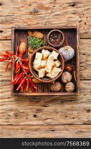 Feta cheese with spice and garlic on old wooden background. Homemade feta cheese with herbs