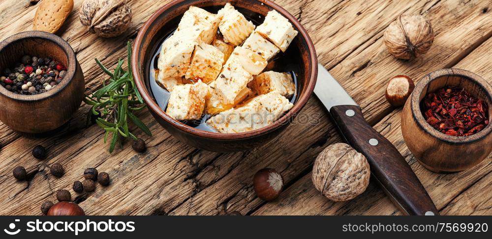 Feta cheese with spice and garlic on old wooden background. Homemade feta cheese with herbs