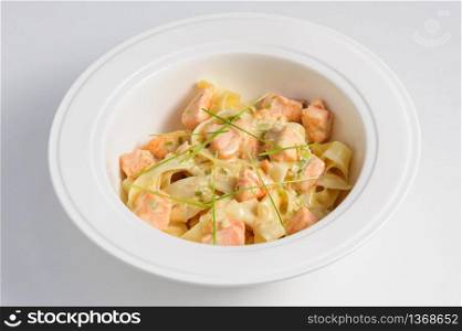Fettuccine with salmon at white plate, top view. Fettuccine with salmon
