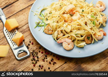 Fettuccini pasta with shrimp on wooden table.Italian food. Plate of pasta with shrimps