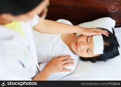 fever child with nurse or doctor measuring temperature of kid sick / child with high fever and laying in bed with hand holding on forehead and cooling gel sheet