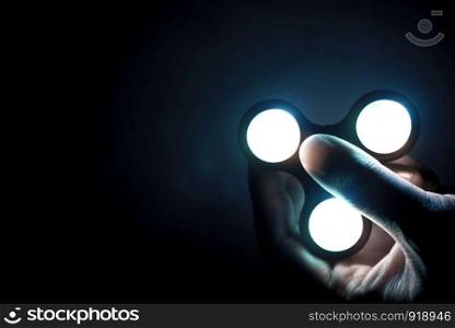 Fidget spinner toy with neon light consist of ball-bearing made from metal or plastic helping people who have trouble with focusing by relieving nervous energy or psychological stress. selective focus