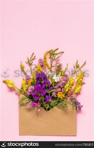 Field colorful rustic vintage flowers in craft envelope on pink background Greeting card Flat Lay Copy space Concept Hello spring. Field colorful rustic flowers in craft envelope on pink background Greeting card Flat Lay Copy space Concept Hello spring