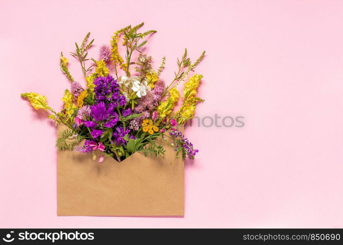 Field colorful rustic vintage flowers in craft envelope on pink background Greeting card Flat Lay Copy space Concept Hello spring. Field colorful rustic flowers in craft envelope on pink background Greeting card Flat Lay Copy space Concept Hello spring