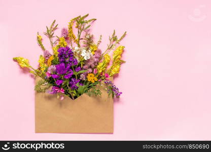 Field colorful rustic vintage flowers in craft envelope on pink background Greeting card Flat Lay Copy space Concept Hello spring. Field colorful rustic flowers in craft envelope on pink background Greeting card Flat Lay Copy space Concept Hello spring