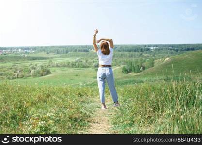  field summer landscape, happy young model. freedom and relaxation concept in summer and spring. woman wearing casual clothes and enjoying travel. rear view. field summer landscape, happy young model. 