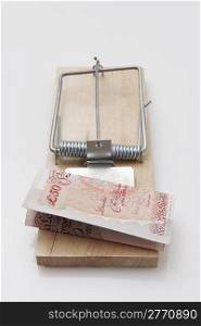 fifty pound note set on a mousetrap on white background