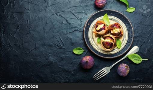 Fig with goat cheese baked with bacon and yogurt sauce.Copy space. Figs roasted in bacon with cheese,space for text