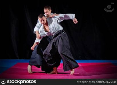 Fight between two aikido fighters on black