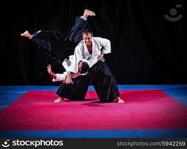 Fight between two aikido fighters on black