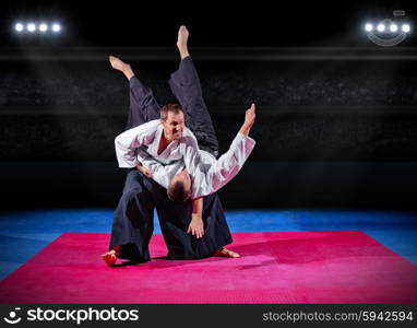 Fight between two martial arts fighters at sports hall