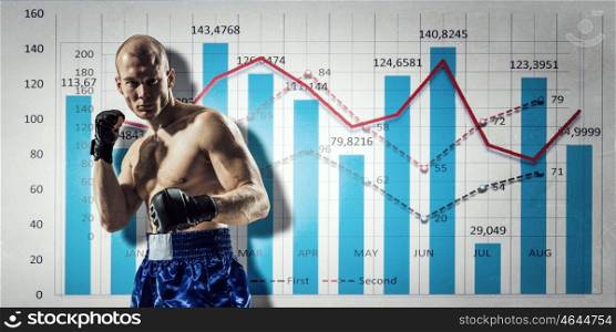 Fighting for sales dynamics. Muscular boxer man over dark background with graphs and diagrams