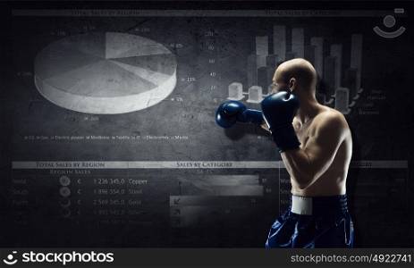 Fighting for sales dynamics. Muscular boxer man over dark background with graphs and diagrams