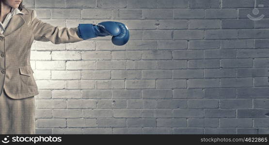 Fighting for success. Young confident businesswoman wearing blue boxing gloves