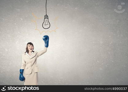 Fighting for success. Young confident businesswoman wearing blue boxing gloves