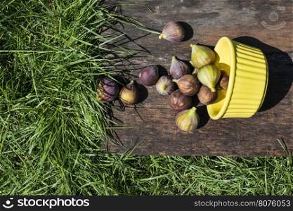 Figs in yellow bowl on wood