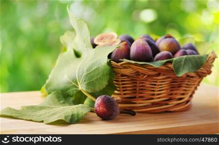 Figs on a wooden basket with fig leaves