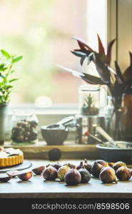 Figs on kitchen table with  baking utensils at window background Preparing Mediterranean fruit. Front view.