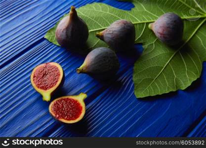 figs raw cutted fruits and fig tree leaves on blue wooden table