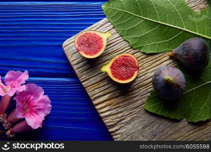 figs raw cutted fruits and fig tree leaves on blue wooden table