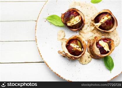 Figs wrapped in fried bacon stuffed with cheese.Copy space. Figs baked in bacon with cheese,space for text