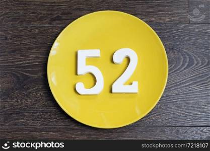 Figure fifty-two at the plate yellow and brown background.. The number fifty-two on the yellow plate.