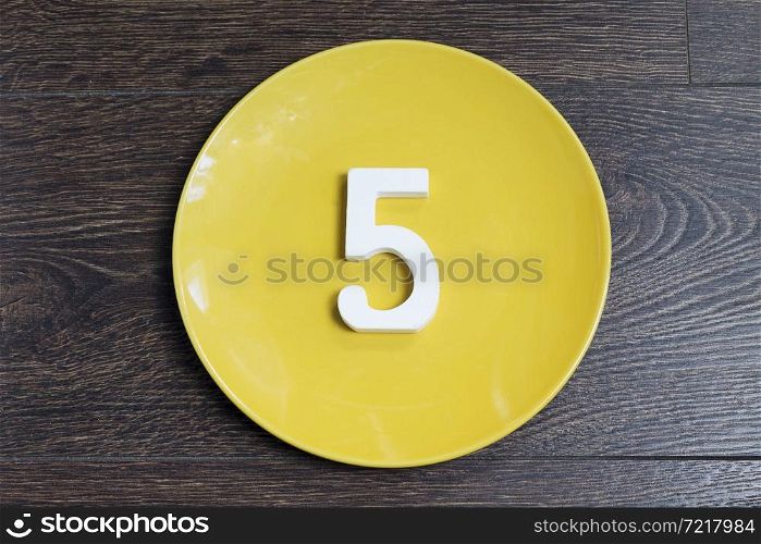 Figure five on the yellow plate and brown background.. Figure five on the yellow plate.